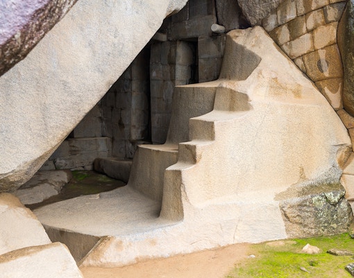 Ancient stone steps at Machu Picchu, Peru, leading into a carved rock chamber.