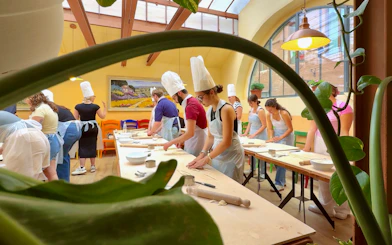 Participants in a cooking class in Siena preparing dough at a long table.
