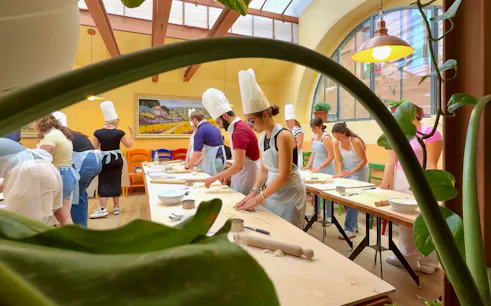 Participants in a cooking class in Siena preparing dough at a long table.