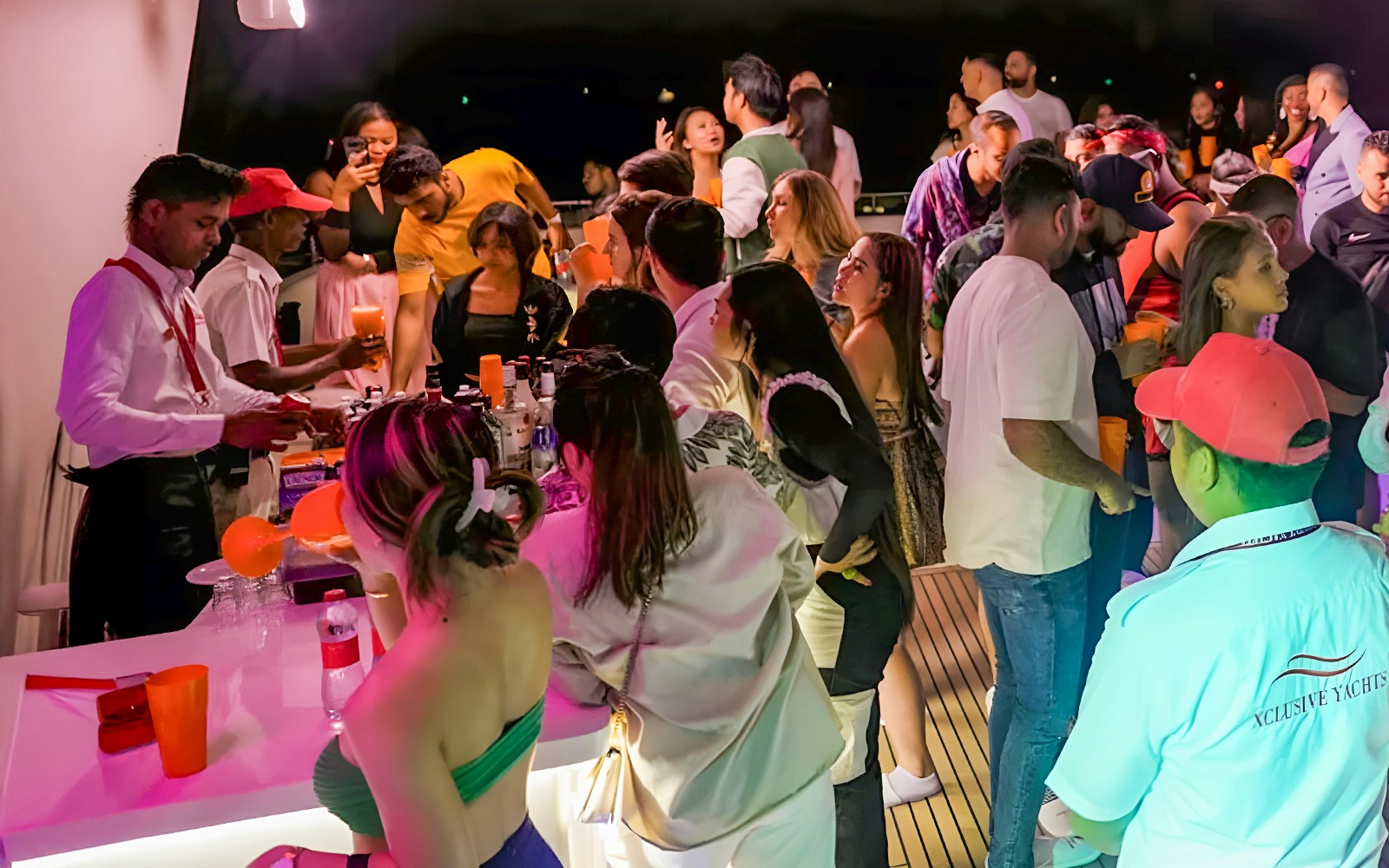 People enjoying drinks at an open bar on a party yacht in Dubai Marina.