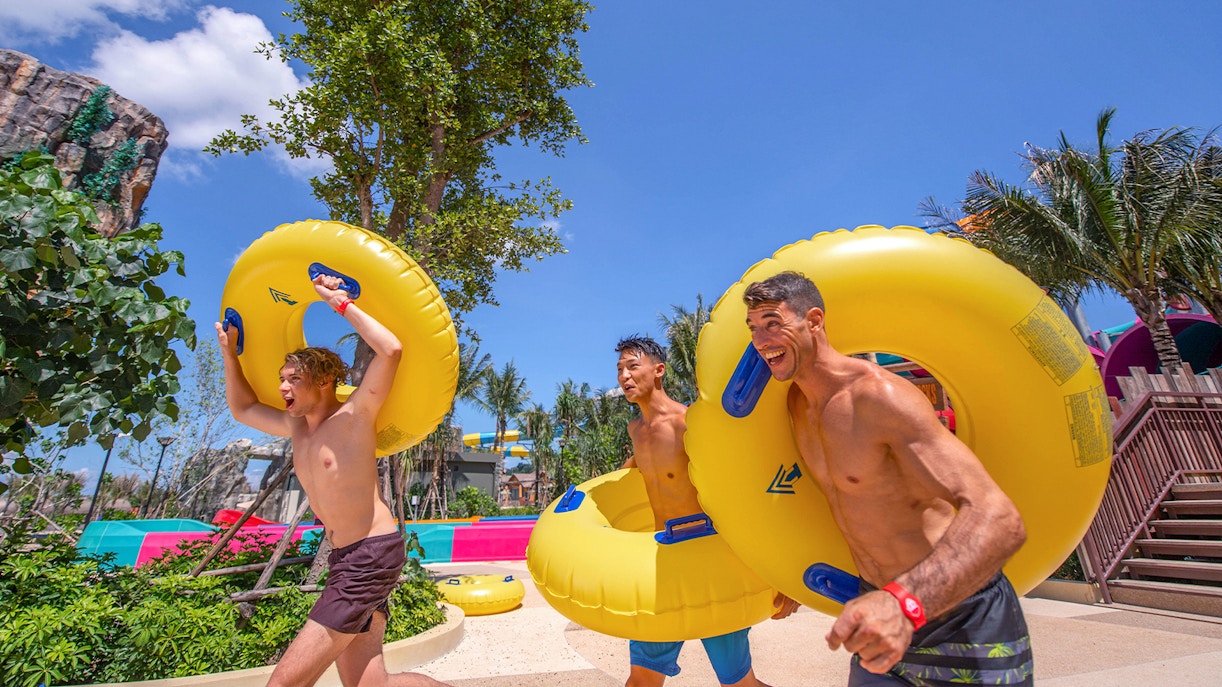 People carrying inflatable tubes towards water slides at Andamanda Phuket.