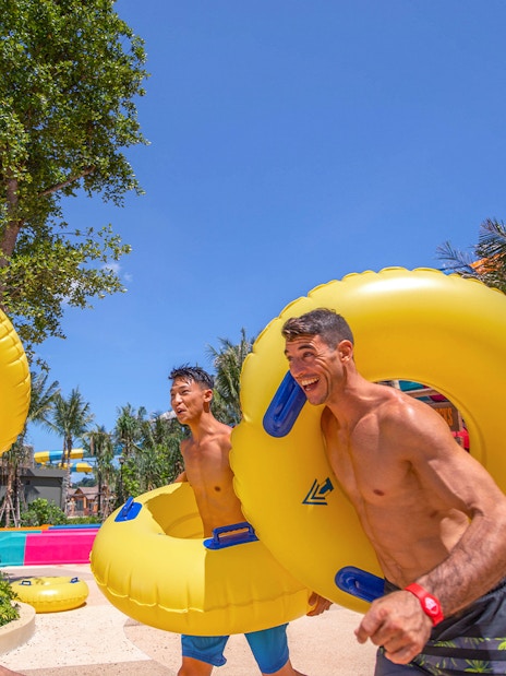 People carrying inflatable tubes to water slides at Andamanda Phuket.