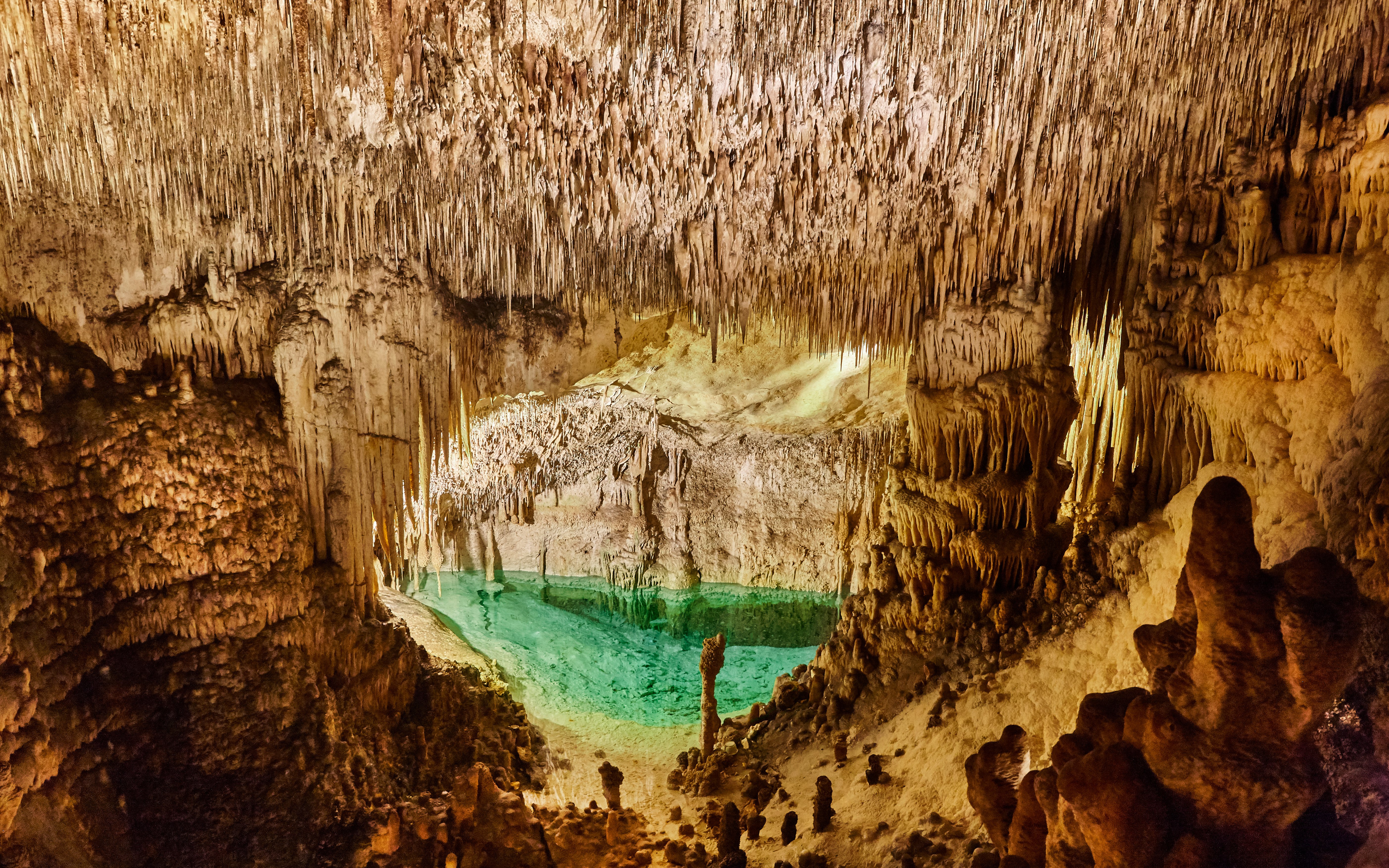 Stalactites and turquoise pool inside Drach Caves, Mallorca.