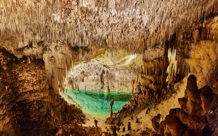 Stalactites and turquoise pool inside Drach Caves, Mallorca.