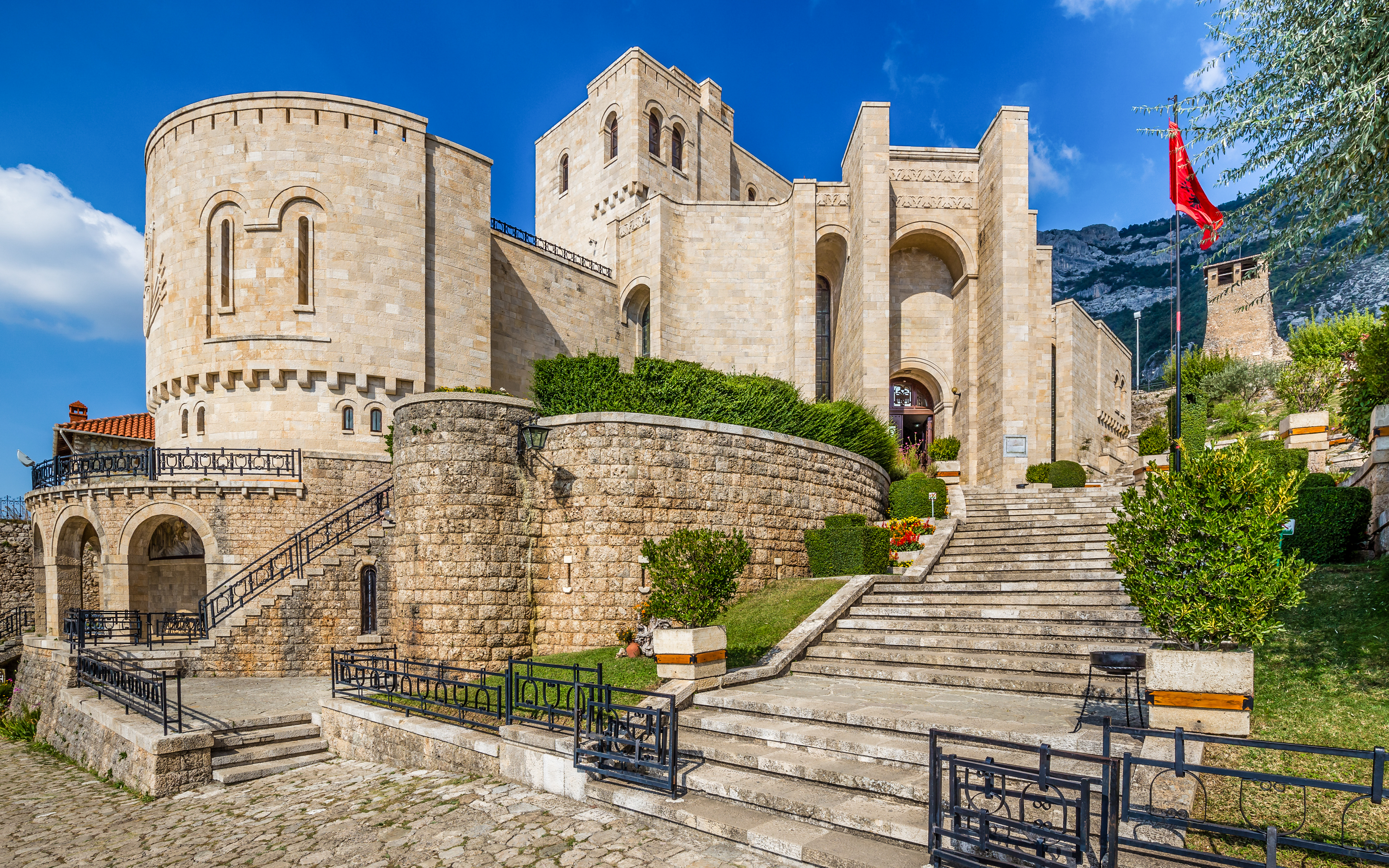 Kruje Castle stone architecture with steps and Albanian flag, Kruje, Albania.