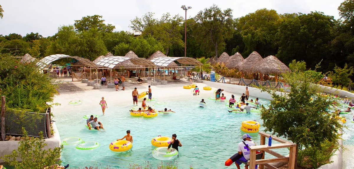 Visitors enjoying the wave pool at Schlitterbahn New Braunfels, surrounded by lush greenery.