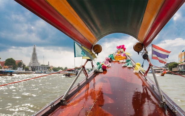 Long-tail boat on Bangkok Yai Canal with Wat Arun in the background.