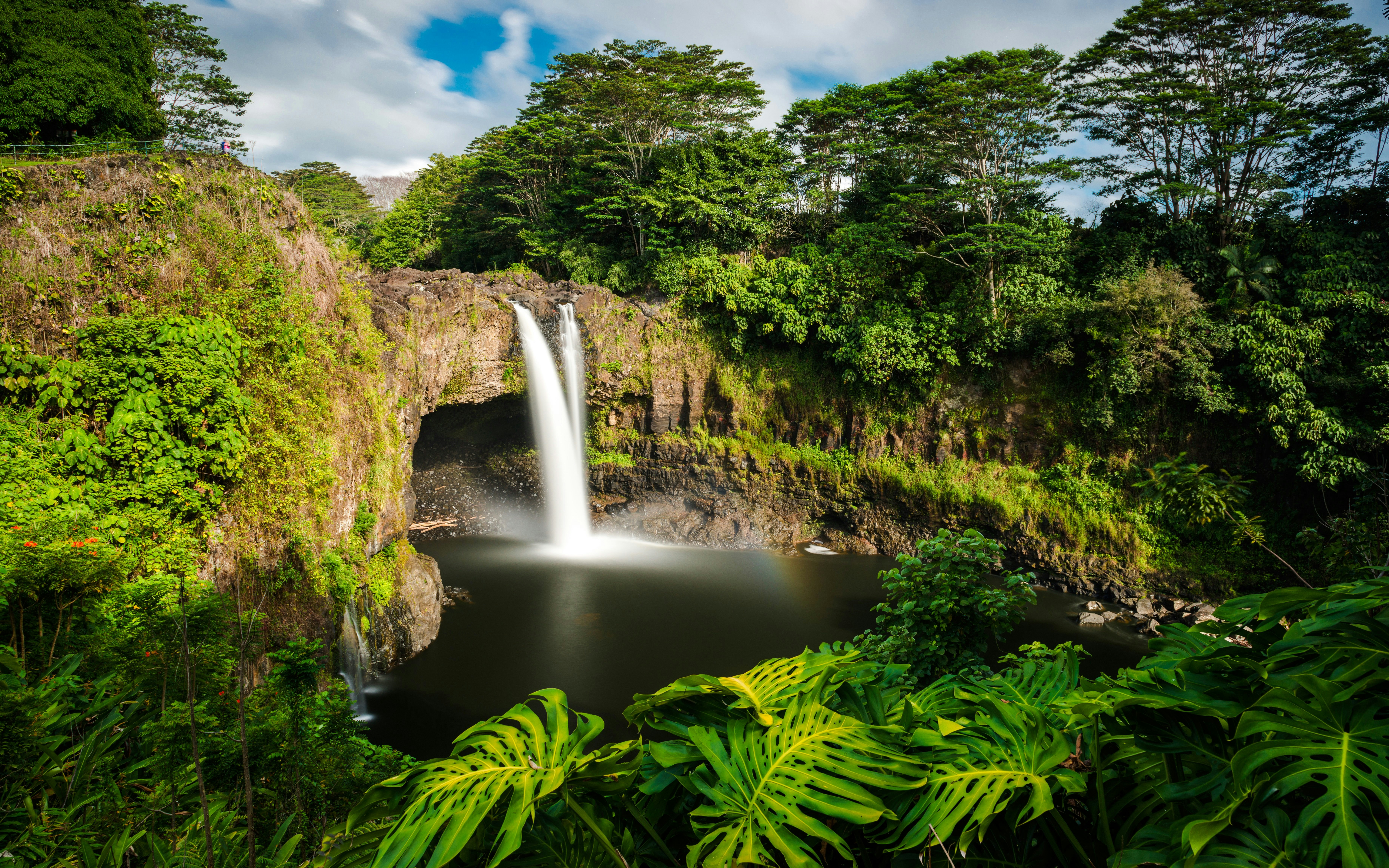 Rainbow Falls cascading into a pool surrounded by lush greenery in Hilo, Wailuku.