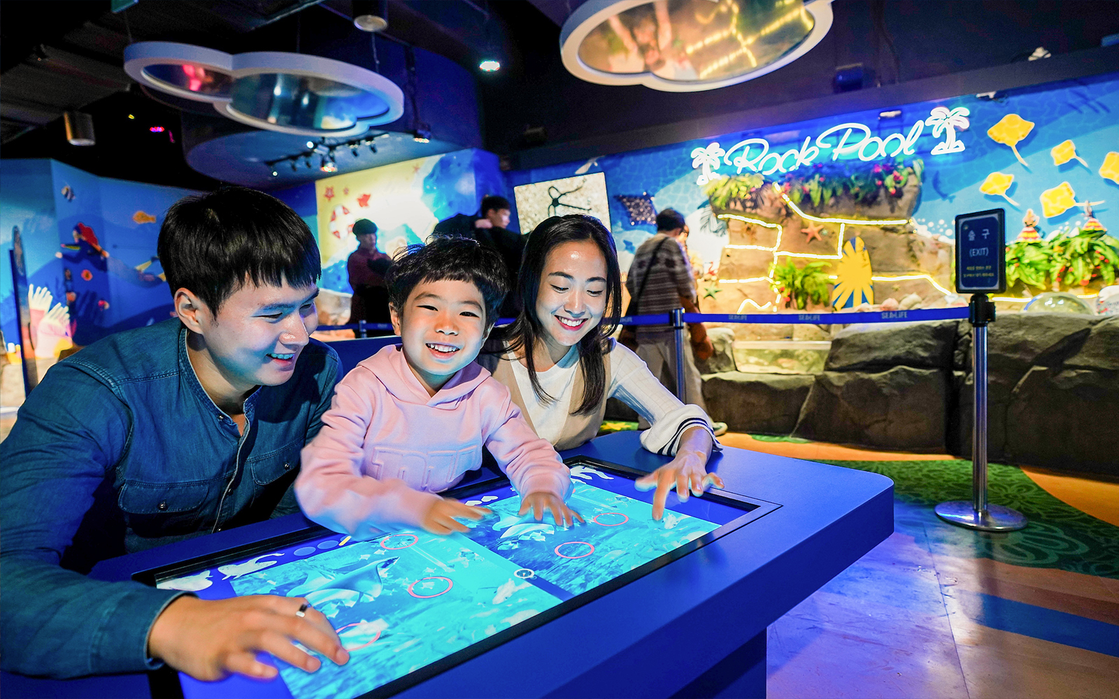Visitors enjoying interactive display at SEA LIFE Busan Aquarium.