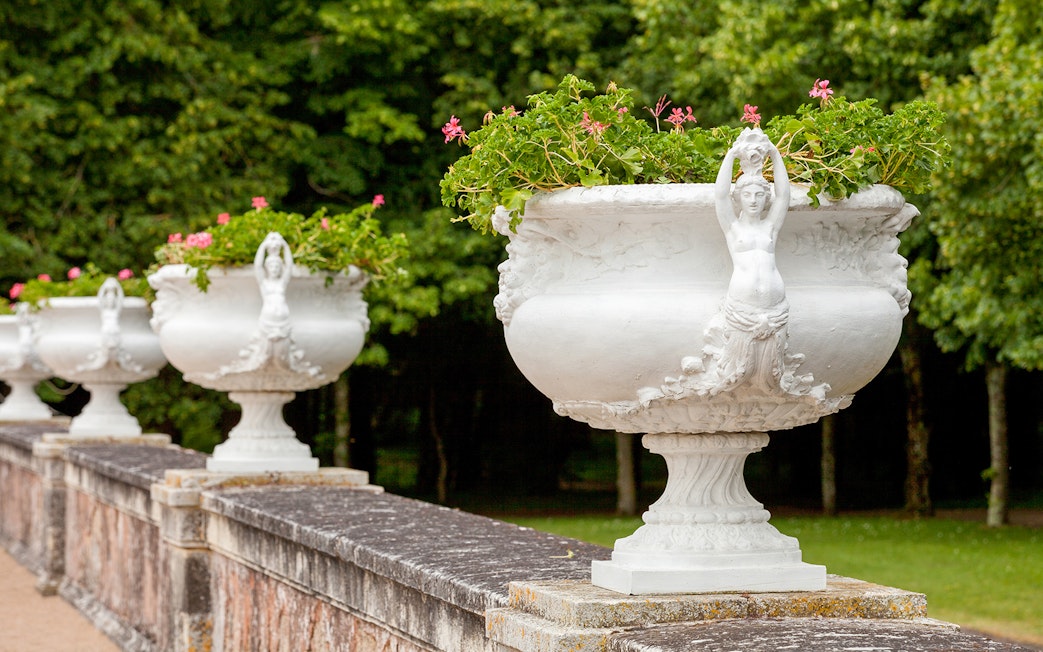 Stone urns with floral decorations at Chenonceau Castle gardens.