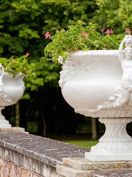 Stone urns with floral decorations at Chenonceau Castle gardens.