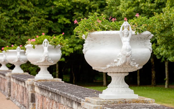 Stone urns with floral decorations at Chenonceau Castle gardens.