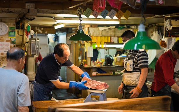 Fish vendor weighing tuna at Tsukiji Outer Market, Tokyo.