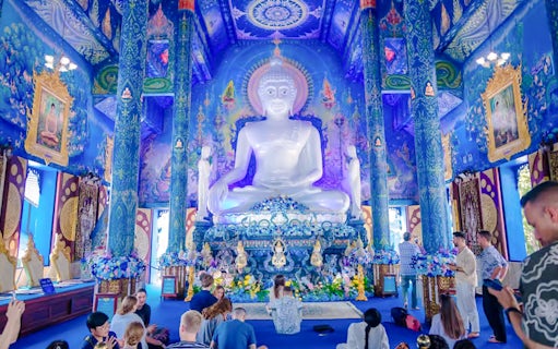 Interior of Blue Temple (Wat Rong Sua Ten) with white Buddha statue and ornate blue decor.