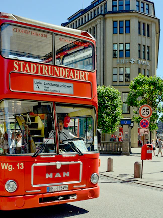 Red double-decker tour bus on city street near Blue Planet Aquarium.
