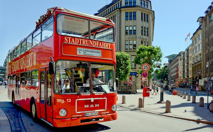 Red double-decker tour bus on city street near Blue Planet Aquarium.