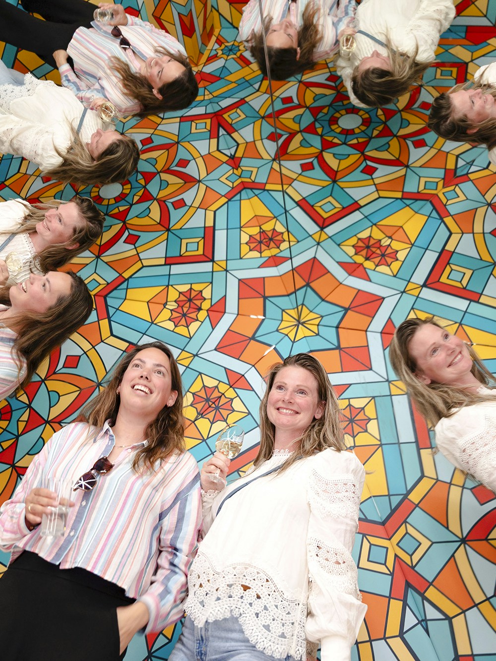 Guests enjoying reflections at Museum of Illusions Amsterdam with colorful geometric patterns.