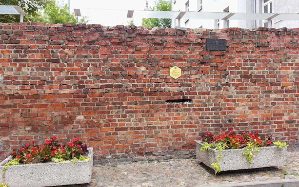 Remnant of Warsaw Ghetto wall with commemorative plaques on a private walking tour of Jewish heritage.