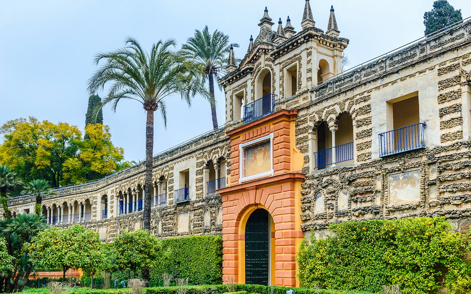 Mudéjar architecture of Alcazar Seville with ornate facade and lush gardens.