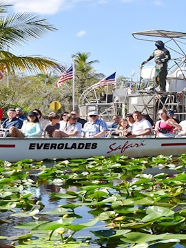 Tourists on an airboat ride through Everglades Safari Park, Miami, surrounded by water lilies.