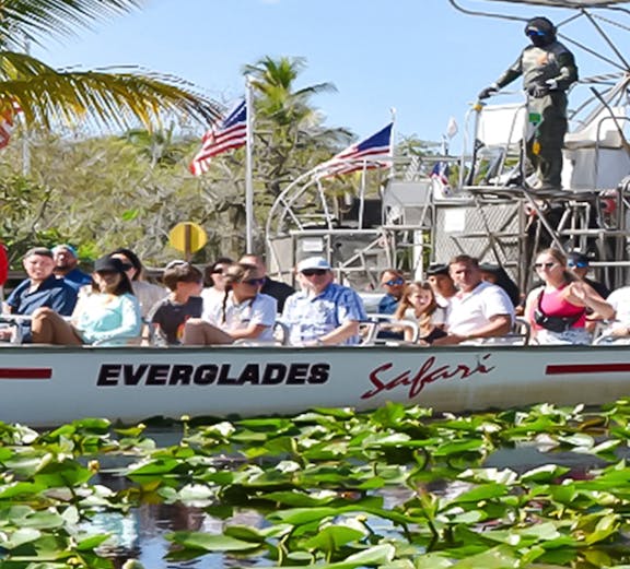 Tourists on an airboat ride through Everglades Safari Park, Miami, surrounded by water lilies.