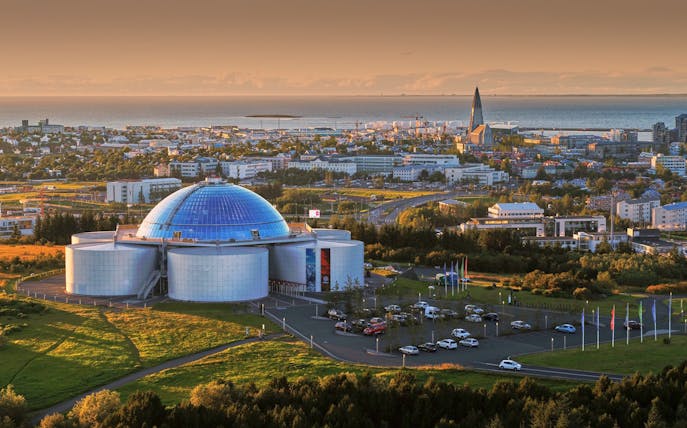 Perlan dome in Reykjavik, Iceland, with cityscape and ocean in the background.