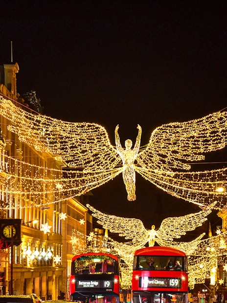 London Christmas lights on Regent Street with festive decorations and bustling holiday shoppers.