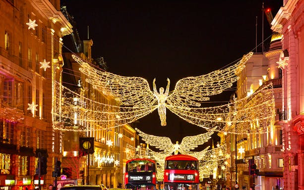 London Christmas lights on Regent Street with festive decorations and bustling holiday shoppers.