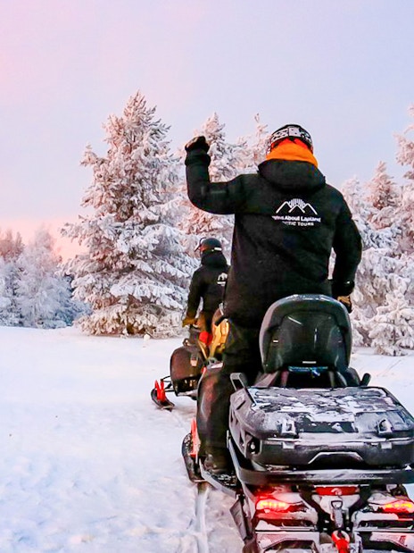 Snowmobilers riding through snowy forest during 1-Hour Snowmobile Safari Adventure from Rovaniemi.