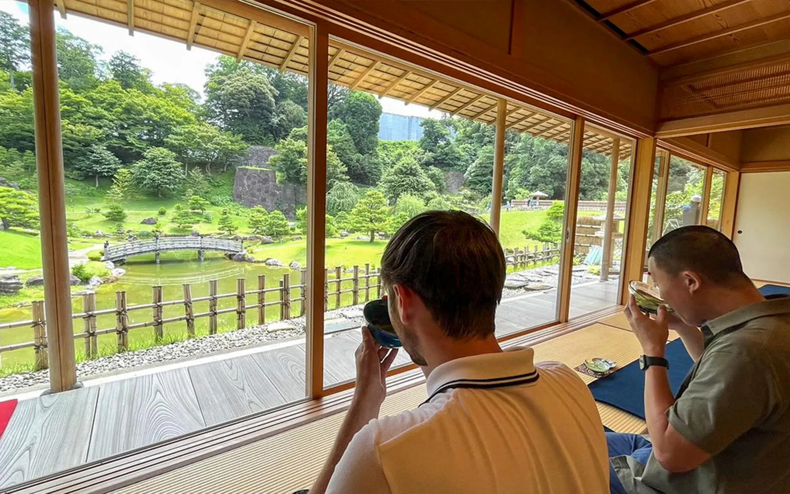 Visitors enjoying matcha tea with a view of a traditional Japanese garden in Kanazawa.