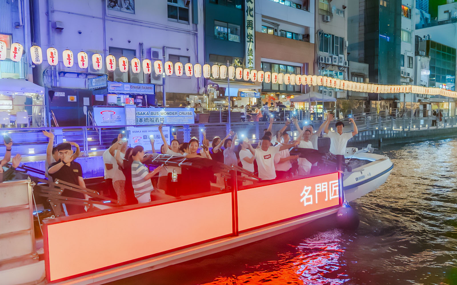 Passengers enjoying a night cruise on the Dotonbori River in Osaka, Japan.