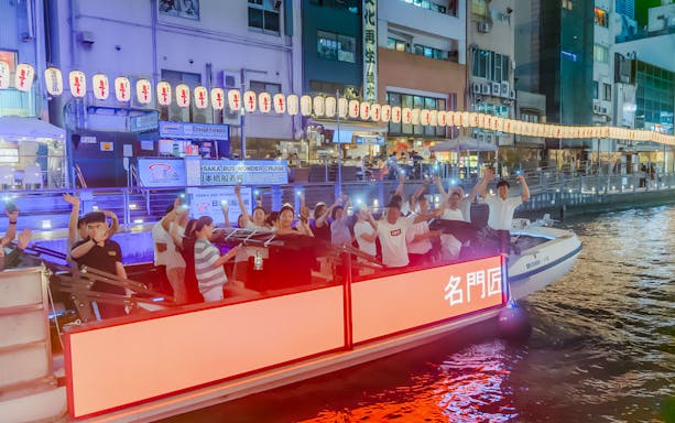 Passengers enjoying a night cruise on the Dotonbori River in Osaka, Japan.