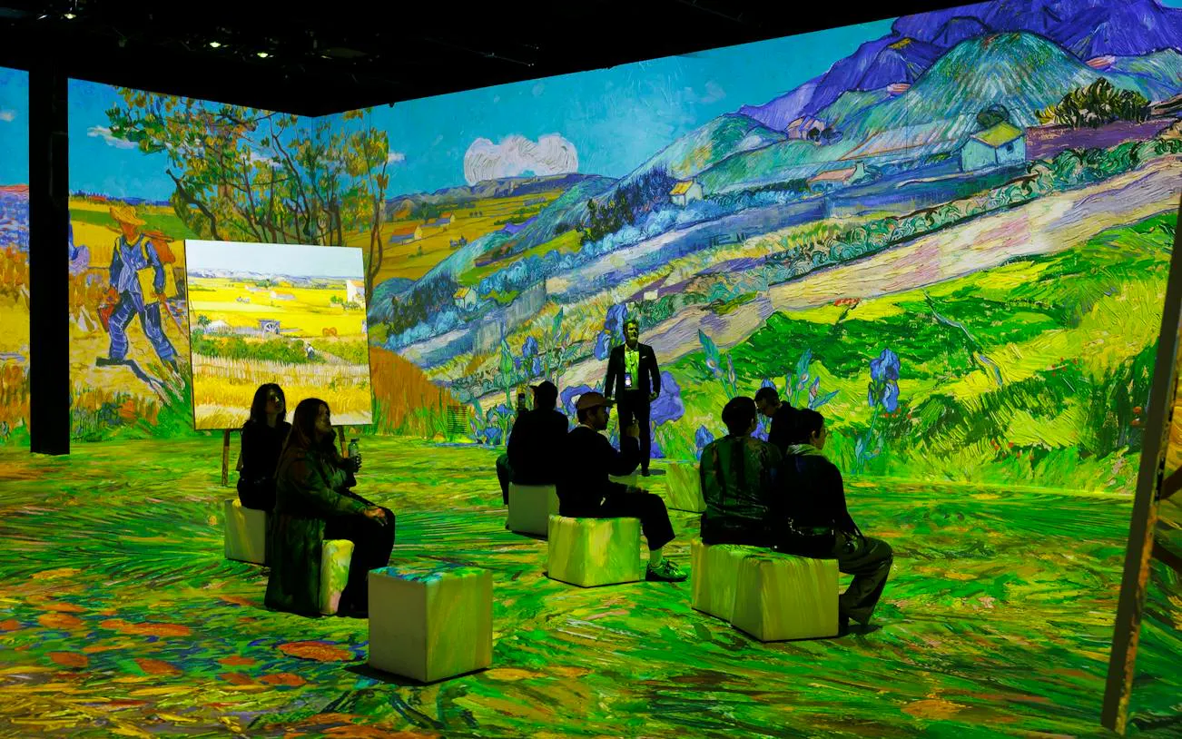 Visitors seated at Van Gogh immersive exhibition in Zurich with vibrant landscape projections.