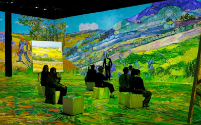 Visitors seated at Van Gogh immersive exhibition in Zurich with vibrant landscape projections.