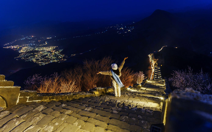 Traveler enjoying night view of illuminated Badaling Great Wall, Beijing.