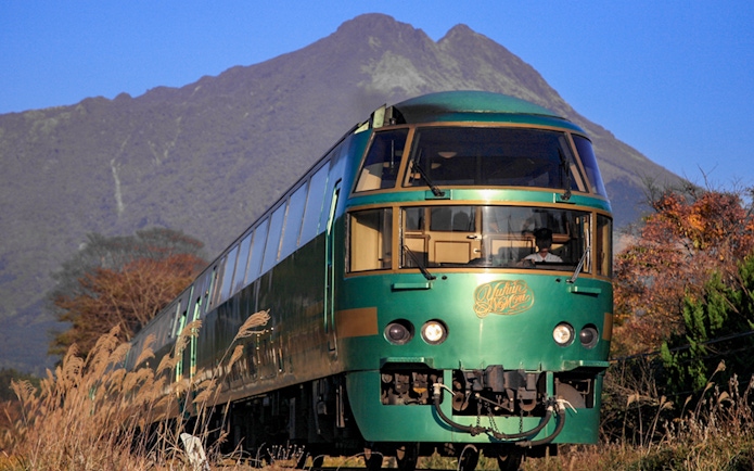 JR train traveling through Kyushu with mountains in the background.