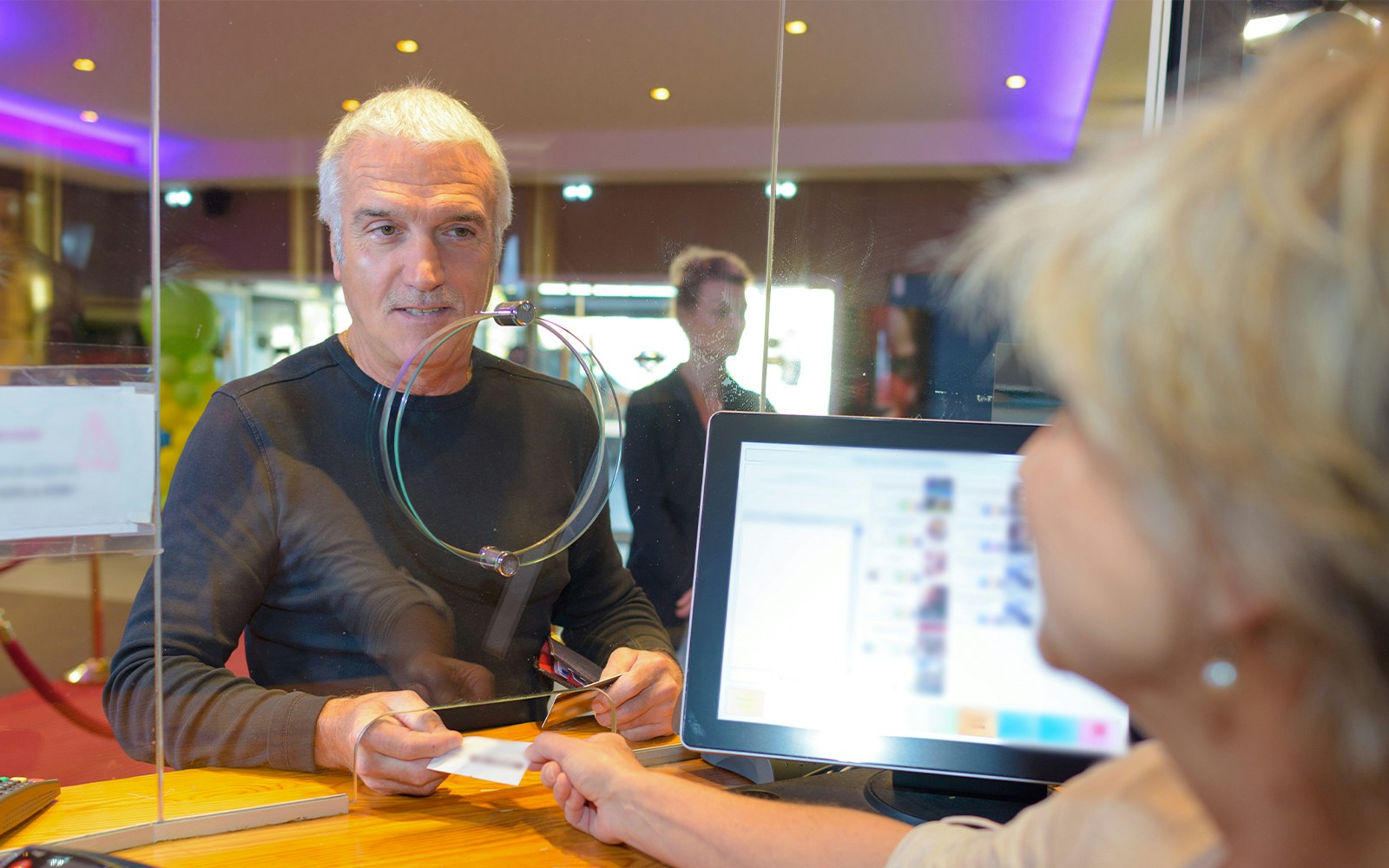 Man receiving ticket at counter with computer screen.
