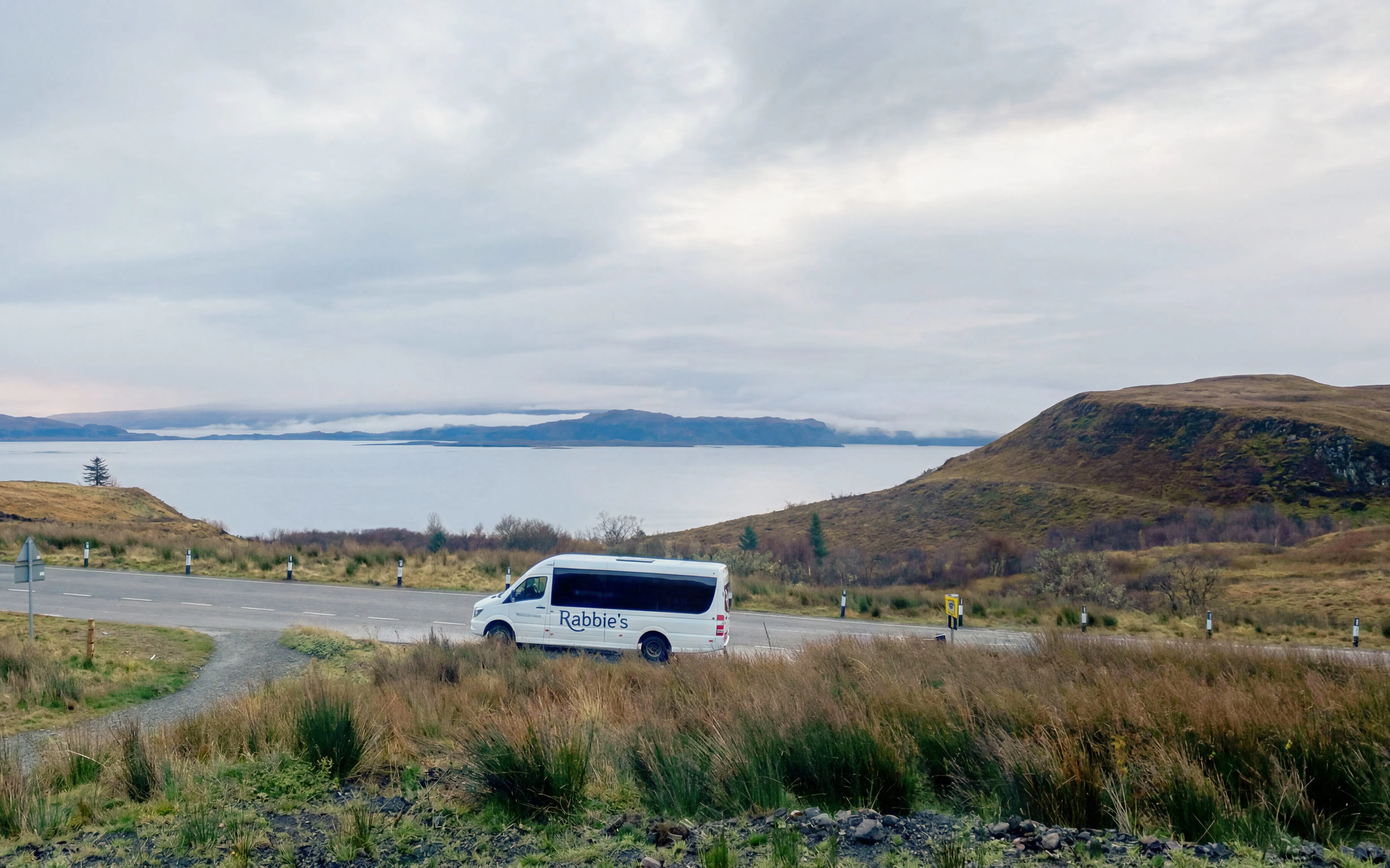 Minibus on scenic road by a lake in the Scottish Highlands.