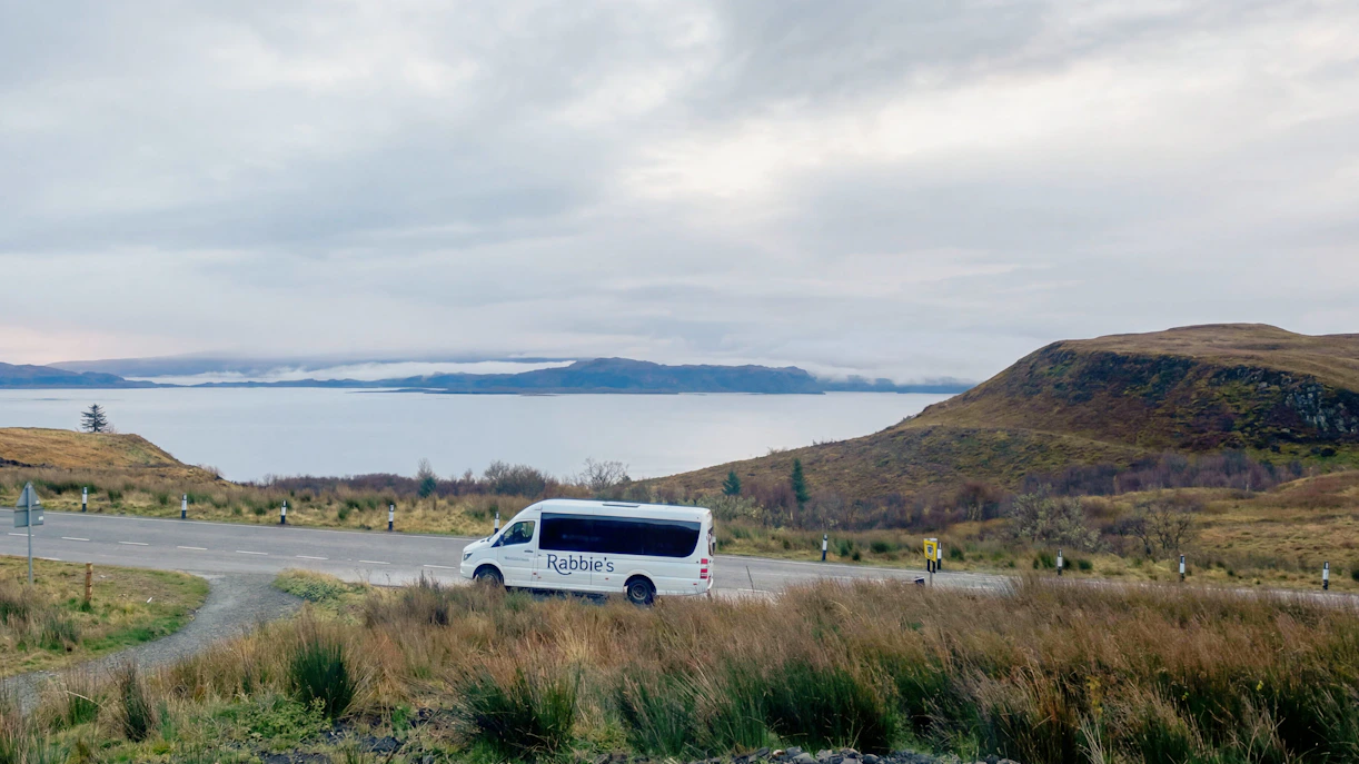 Minibus on scenic road by a lake in the Scottish Highlands.
