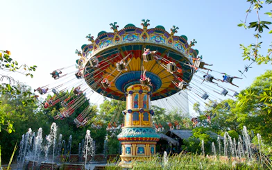 Swing ride at Isla Magica's The Flight of the Falcon, surrounded by trees and fountains.
