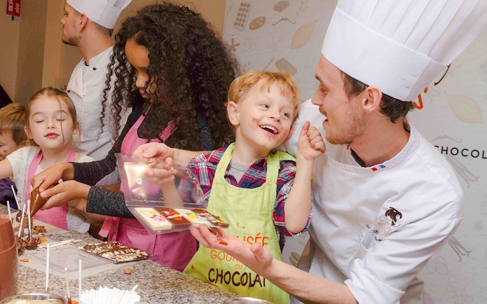 Kids making chocolate with a chef at Choco-Story Paris.
