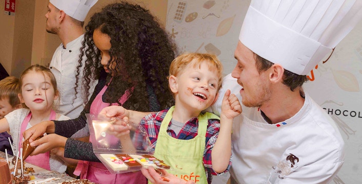 Chocolate chef guiding children in a hands-on workshop at Choco-Story Paris.