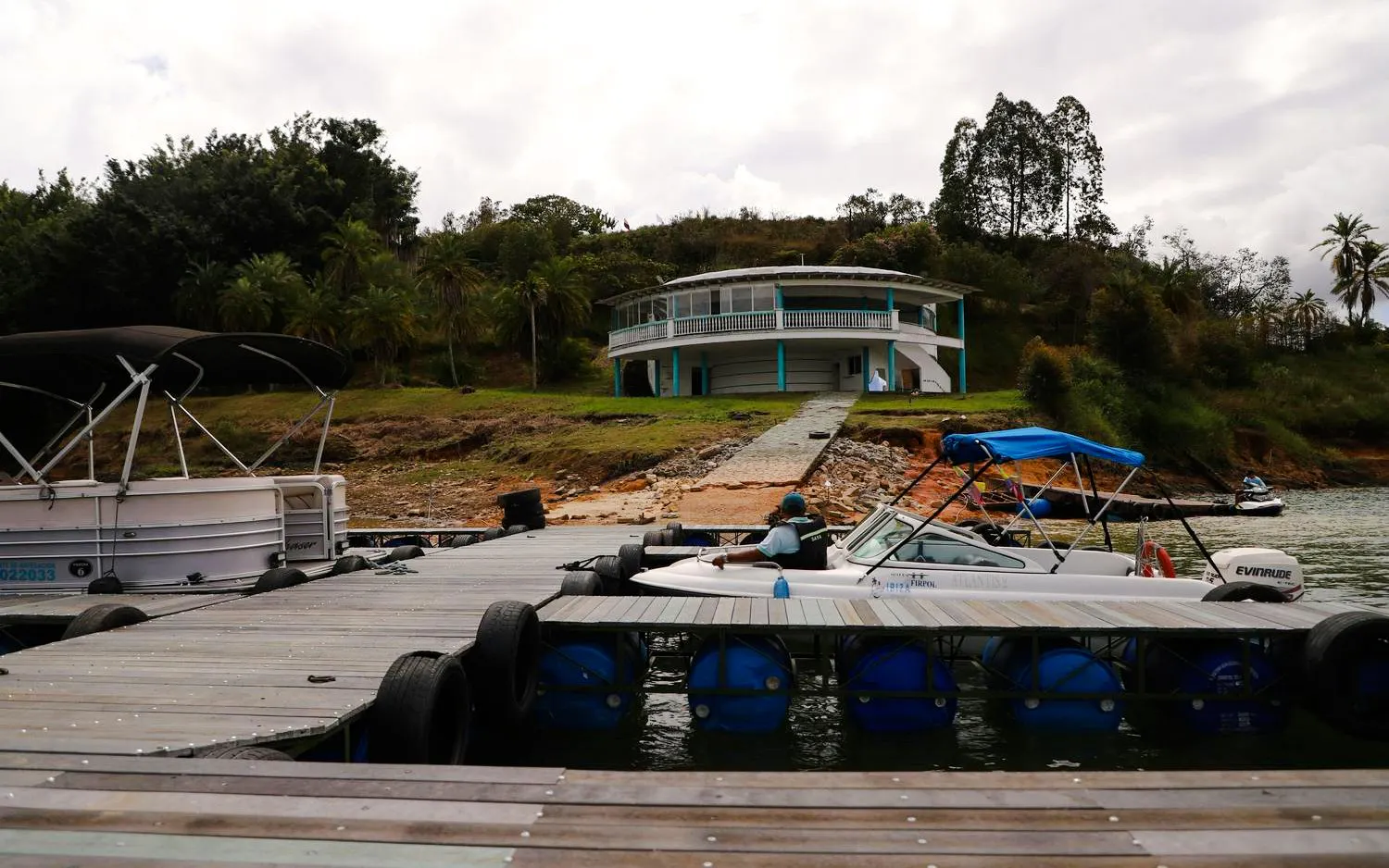 Waterfront view of Hacienda La Manuela on Guatapé Reservoir, Colombia, with boats docked nearby.
