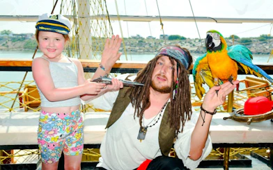 Child with pirate and parrot on Pirate Ship Cruise in Antalya, Turkey.