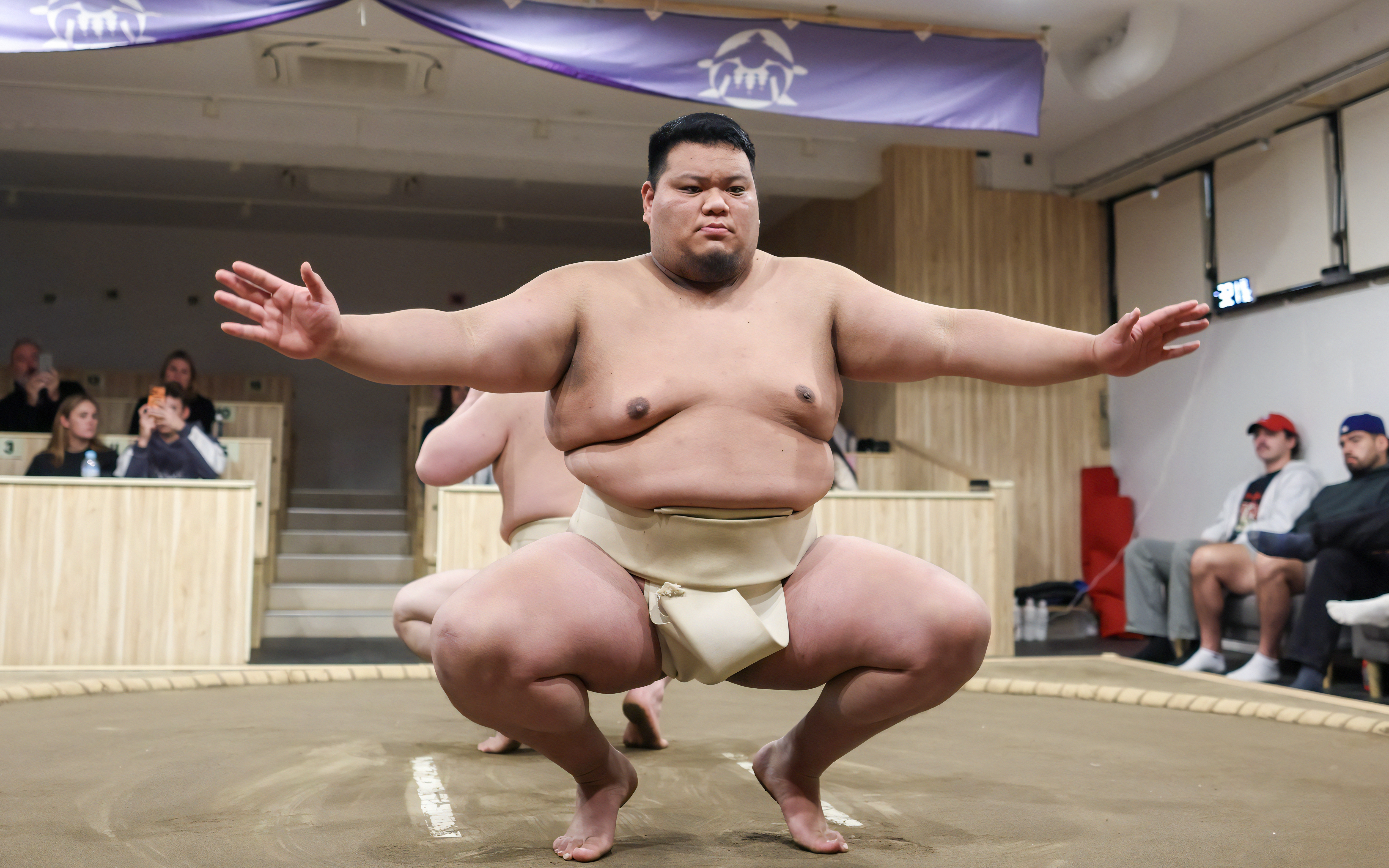 Sumo wrestler crouches in preparation for a match in a Tokyo arena.