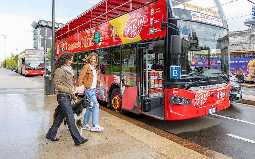 Friends boarding City Sightseeing Milan Hop On Hop Off Bus with a dog on leash.