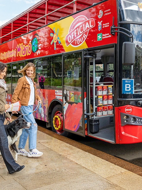 Friends boarding City Sightseeing Milan Hop On Hop Off Bus with a dog on leash.