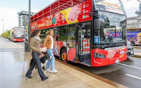 Friends boarding City Sightseeing Milan Hop On Hop Off Bus with a dog on leash.