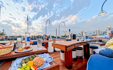 Open-air dining on Nile Dahabiya cruise in Cairo with view of Cairo Tower.