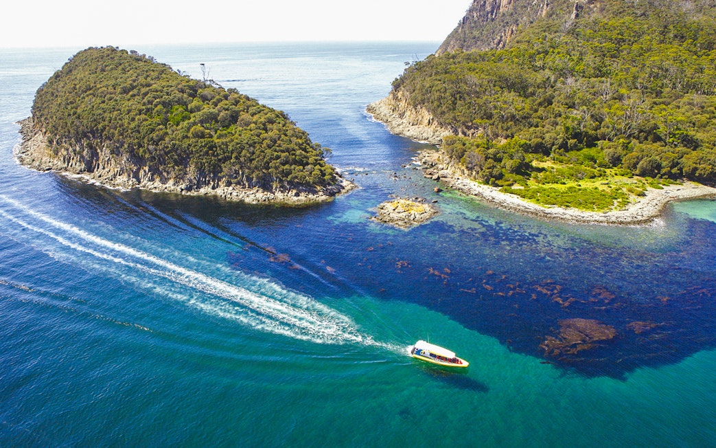Boat cruising between lush islands on Bruny Island Wilderness Cruise, Tasmania.
